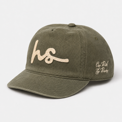 An olive green cotton baseball cap with a curved brim, featuring a glittery beige embroidered 'hs' logo on the front and 'One Rich Life Throug' in white script on the side, set against a light gray background.