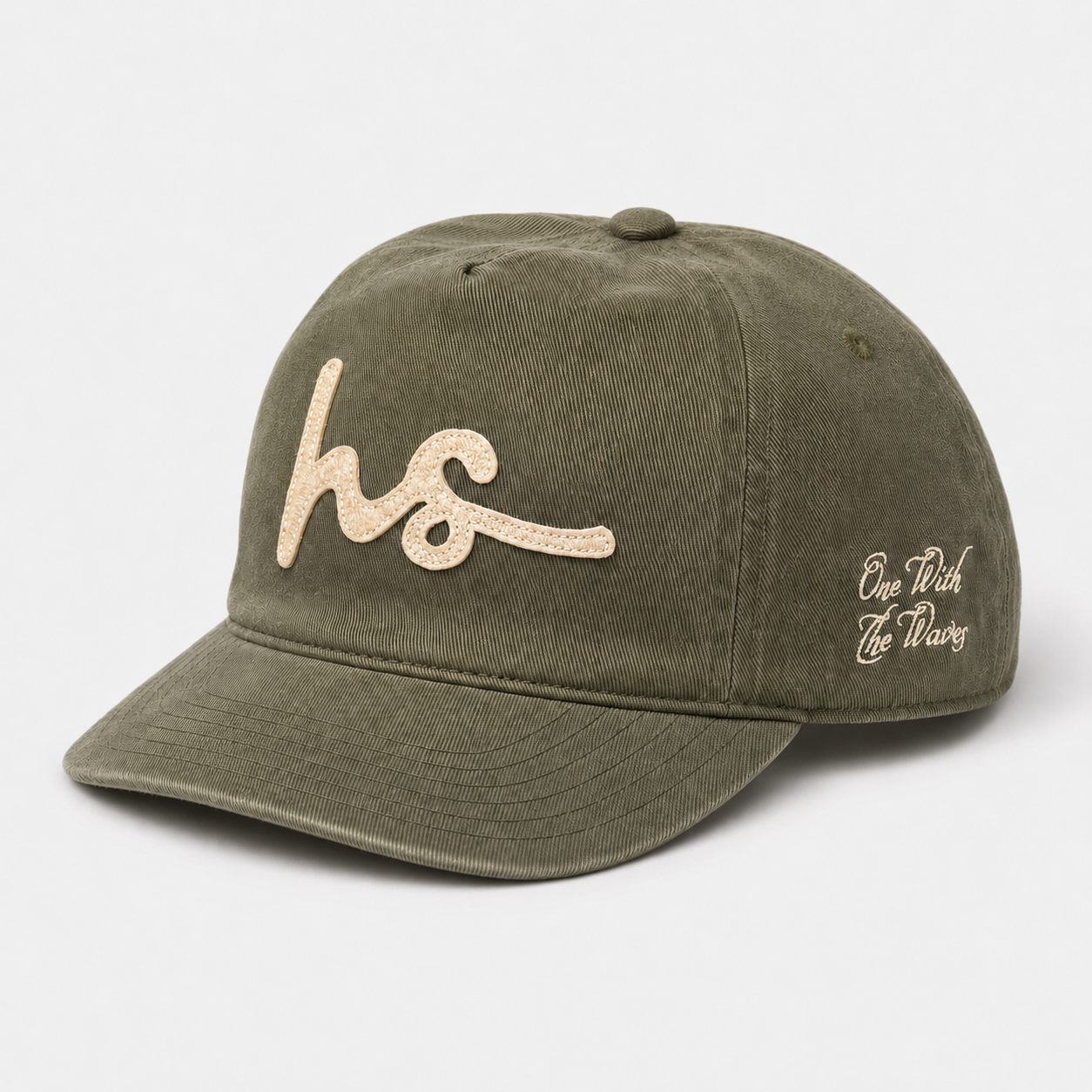 An olive green cotton baseball cap with a curved brim, featuring a glittery beige embroidered 'hs' logo on the front and 'One Rich Life Throug' in white script on the side, set against a light gray background.